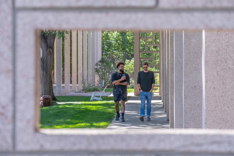 Two male students walk along a campus path.