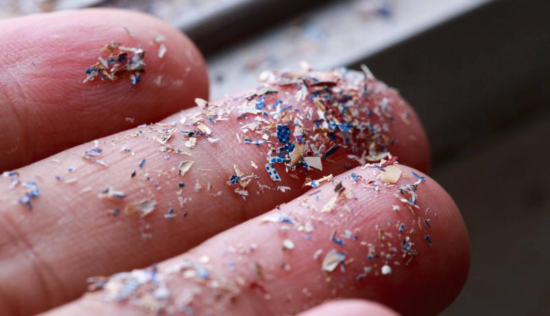 A close-up of a hand holding tiny pieces of plastic.