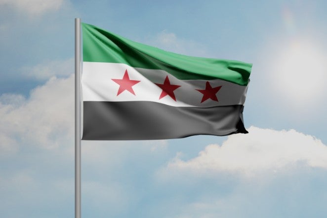 Picture of a CGI Syrian Flag waving in a blue sky.