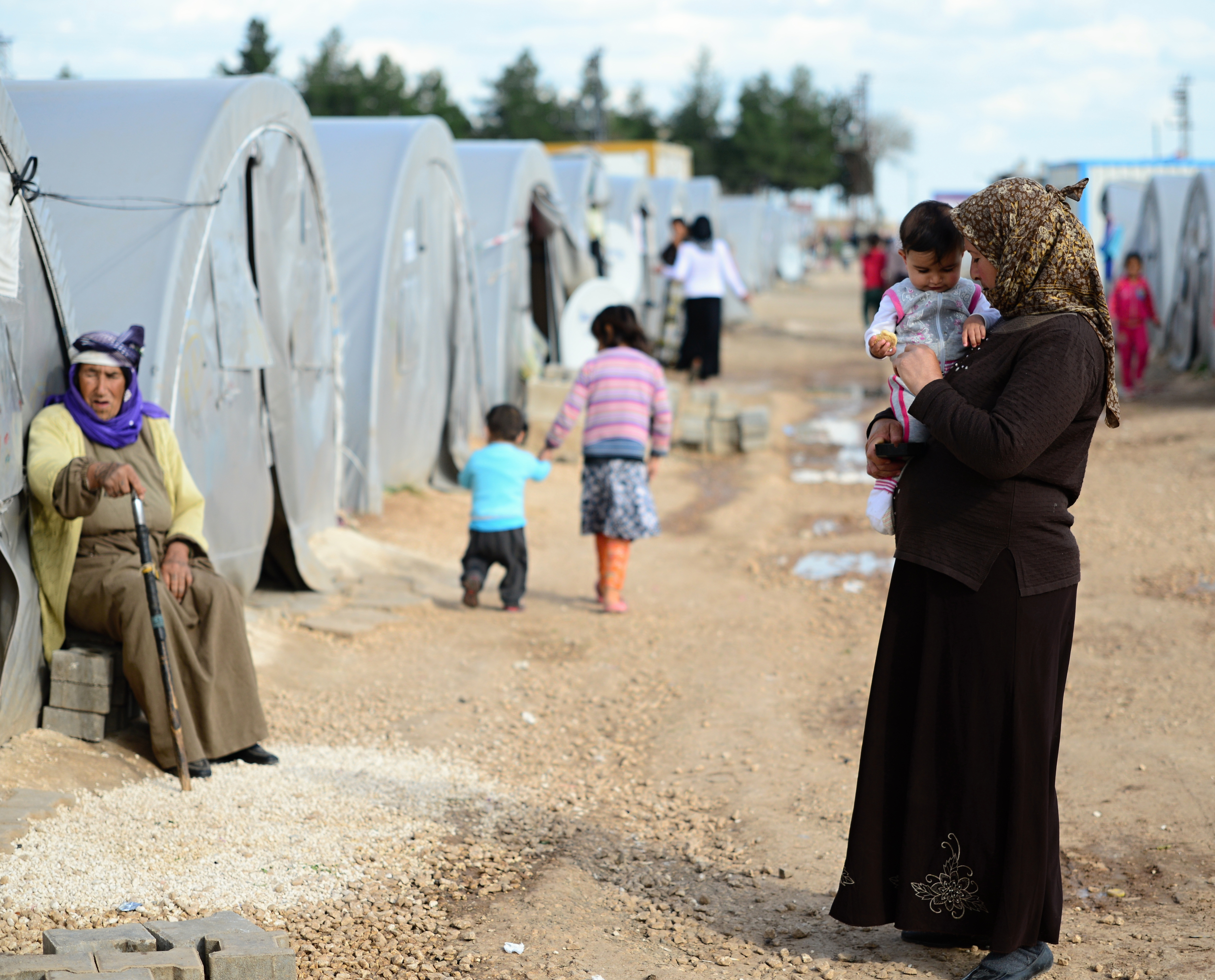 A woman stands holding her child at a Syrian refugee camp in Turkey.