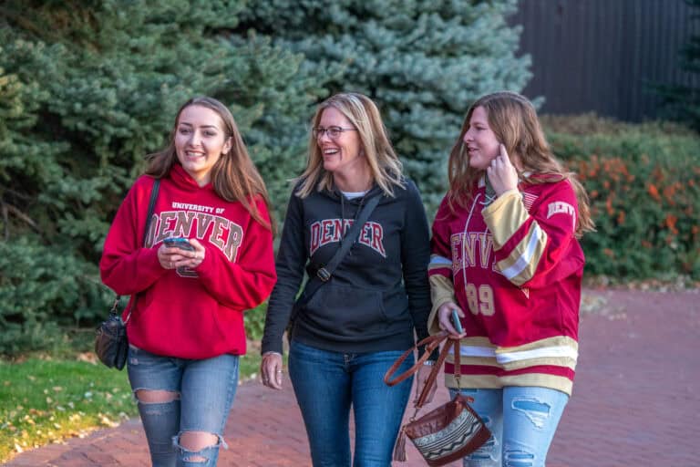 A parent walking with her two children where everyone is wearing DU attire.